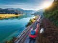 Aerial view of red train moving near river in alpine mountains Royalty Free Stock Photo