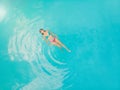 Aerial view of a relaxed young woman in the transparent turquoise sea. Top view of slim woman relaxing in hotel pool