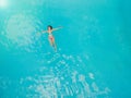 Aerial view of a relaxed young woman in the transparent turquoise sea. Top view of slim woman relaxing in hotel pool