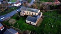 Aerial view of a residential house surrounded by lush green trees and foliage in the foreground Royalty Free Stock Photo