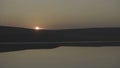 Aerial view of the rising sun on the horizon over the hill above a calm ocean or sea. Shot. Beautiful morning landscape Royalty Free Stock Photo