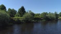 Aerial view of a river in summer village and an old wooden house. Shot. Forest and small house surrounded by green trees Royalty Free Stock Photo