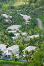 Aerial view riverside white painted tropical villas swimming pool, lounge chairs surrounding lush green coconut palm trees, row Royalty Free Stock Photo