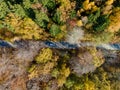 Aerial view of road in autumn forest. Fall landscape with road, red, yellow and green trees. Cars passing on road. Royalty Free Stock Photo