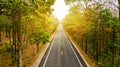 Aerial view of road in autumn forest at sunset. Amazing landscape with rural road, trees with red and orange leaves in day. Royalty Free Stock Photo