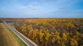 Aerial view of road in autumn forest at sunset. Amazing landscape with rural road, trees with red and orange leaves in a Royalty Free Stock Photo