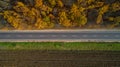 Aerial view of road in autumn forest at sunset. Amazing landscape with rural road, trees with red and orange leaves in a Royalty Free Stock Photo