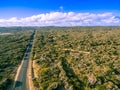 Aerial view of road in beautiful Australian countryside on bright summer day with wind farm in the distance. Royalty Free Stock Photo