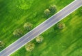 Aerial view of road through beautiful green field at sunset Royalty Free Stock Photo