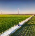 Aerial view of road on beautiful summer field at sunset. Landscape with rural road, wind power turbines. Road through the field. T Royalty Free Stock Photo