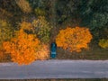 Aerial view of road with blurred car in autumn forest at sunset. Amazing landscape with rural road, trees with red and Royalty Free Stock Photo