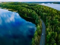 Aerial view of road with cars between green forest and blue lake water in Finland Royalty Free Stock Photo