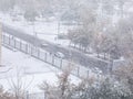 Aerial view of road, cars, trees and buildings covered in snow during winter season and first snowfall in city. Royalty Free Stock Photo