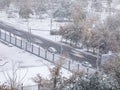 Aerial view of road, cars, trees and buildings covered in snow during winter season and first snowfall in city Royalty Free Stock Photo
