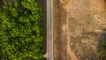 Aerial view of a road that cuts through a lush forest, on the other side is an area