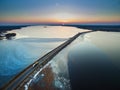 Aerial view of road in the frozen lake with moving cars on sunset. Royalty Free Stock Photo