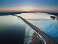 Aerial view of road in the frozen lake with moving cars on sunset, winter view Royalty Free Stock Photo