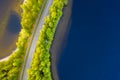 Aerial view of road between green summer forest and blue lake in Finland