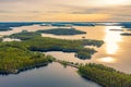 Aerial view of road between green summer forest and blue lake in Finland. Summer sunset lanscape