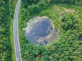 Aerial view on road, lake with reflections and forest