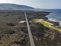 Aerial view of a road that runs through lava fields between the indented coastline of Lanzarote. Spain