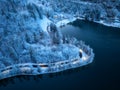 Aerial view of road, snowy forest, lake, street lights at night
