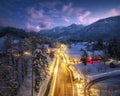 Aerial view of road, snowy mountains, street lights at night