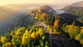 Aerial view of road between yellow and red autumn trees, morning fog, sunrise. Autumn landscape in the mountains. Autumn Royalty Free Stock Photo
