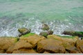 Aerial view of rock and green color sea waves and water forms.