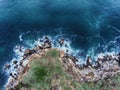 Aerial view of rocky coastline with crop fields and crashing wa