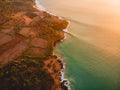 Aerial view of rocky shore with surfers, waves and warm sunset. Royalty Free Stock Photo