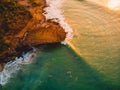 Aerial view of rocky shore with surfers, waves and warm sunset. Drone shot in Bali Royalty Free Stock Photo