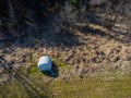 Aerial view of a rolled up hay bale wrapped in plastic foil beside a forest