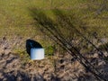 Aerial view of a rolled up hay bale wrapped in plastic foil beside a forest