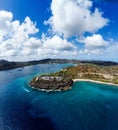 Aerial view of the round shore of green island bordering blue ocean water Royalty Free Stock Photo