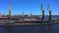 Aerial view of a row of construction or cargo cranes on the river bank. Ship docks off Kanonersky Island.