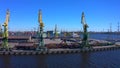 Aerial view of a row of construction or cargo cranes on the river bank. Ship docks off Kanonersky Island.