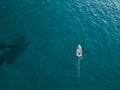 Aerial view of a rowing boat seen from above, powered by an engine. Blue sea that surrounds a boat that crosses it