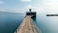 Aerial view of a ruined old pier and azure calm endless sea. Shot. Flying along narrow abandoned pier on blue sky