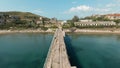 Aerial view of a ruined old pier and azure calm endless sea. Shot. Flying along narrow abandoned pier on blue sky Royalty Free Stock Photo