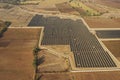 Aerial view of a rural landscape featuring a large solar array and the backdrop of a mountain range