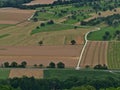 Aerial view of rural road leading through brown and green agricultural fields with trees on the foothills of Swabian Alb. Royalty Free Stock Photo