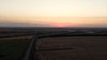 Aerial view of rural road passing through agricultural land and cultivated fields. Footage. Concept of agrarian industry