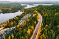 Aerial view of rural road with red car in yellow and orange autumn forest with blue lake Royalty Free Stock Photo