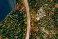 Aerial view of rural road with red car in yellow and orange autumn forest with blue lake Royalty Free Stock Photo