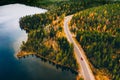 Aerial view of rural road with red car in yellow and orange autumn forest with blue lake Royalty Free Stock Photo