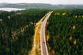 Aerial view of rural road with red car in yellow and orange autumn forest with blue lake Royalty Free Stock Photo