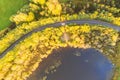 Aerial view of rural road with white car in yellow and orange autumn forest. Aerial road near the lake with moving car. Top view Royalty Free Stock Photo
