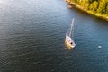 Aerial view of sailing white yacht in sea next to pine forest Royalty Free Stock Photo