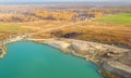 Aerial view of a sand mining quarry on a turquoise lake with posted construction equipment and excavators.